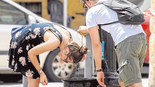 Una joven se refresca en una fuente pública