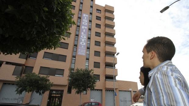 Una pareja mira el cartel de unos pisos en venta en Alicante