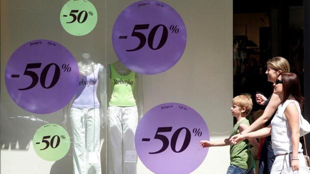 Transeúntes pasan junto a un escaparate comercial en Valencia