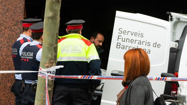 Mossos d'Esquadra y personal de los Servicios Funerarios retiran el cuerpo sin vida del hombre que ha fallecido tiroteado este mediodía en la calle Comte d'Urgell