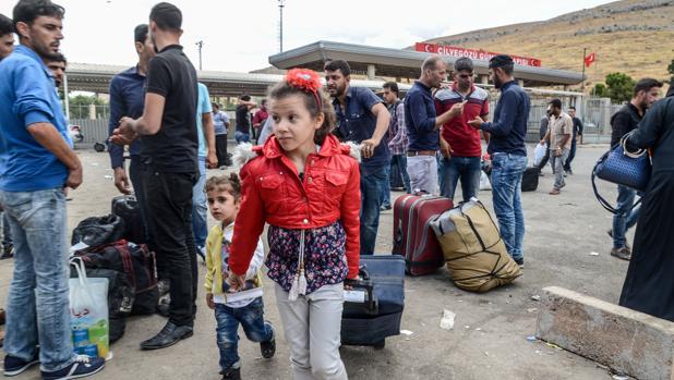 Varias familias sirias se llevan sus pertenencias mientras cruzan la puerta fronteriza al lado turco el 9 de octubre de 2017 en el distrito de Reyhanli en Hatay
