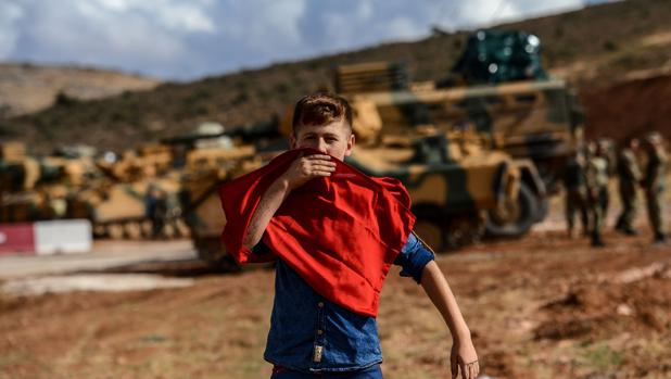 Un joven besa una bandera nacional turca mientras se acerca a los soldados y vehículos blindados turcos durante una manifestación en apoyo de la operación de Idlib del ejército turco cerca de la frontera entre Turquía y Siria, cerca de Reyhanli, Hatay