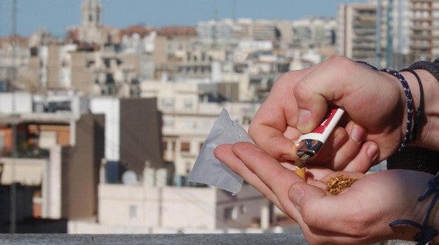 Un joven lia un cigarrillo