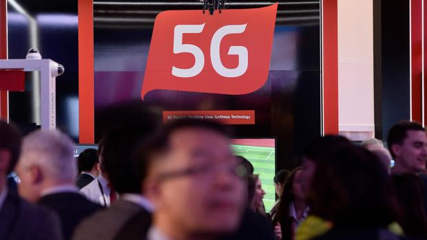 Personas pasan por un stand en donde se informa de las capacidades de las redes 5G